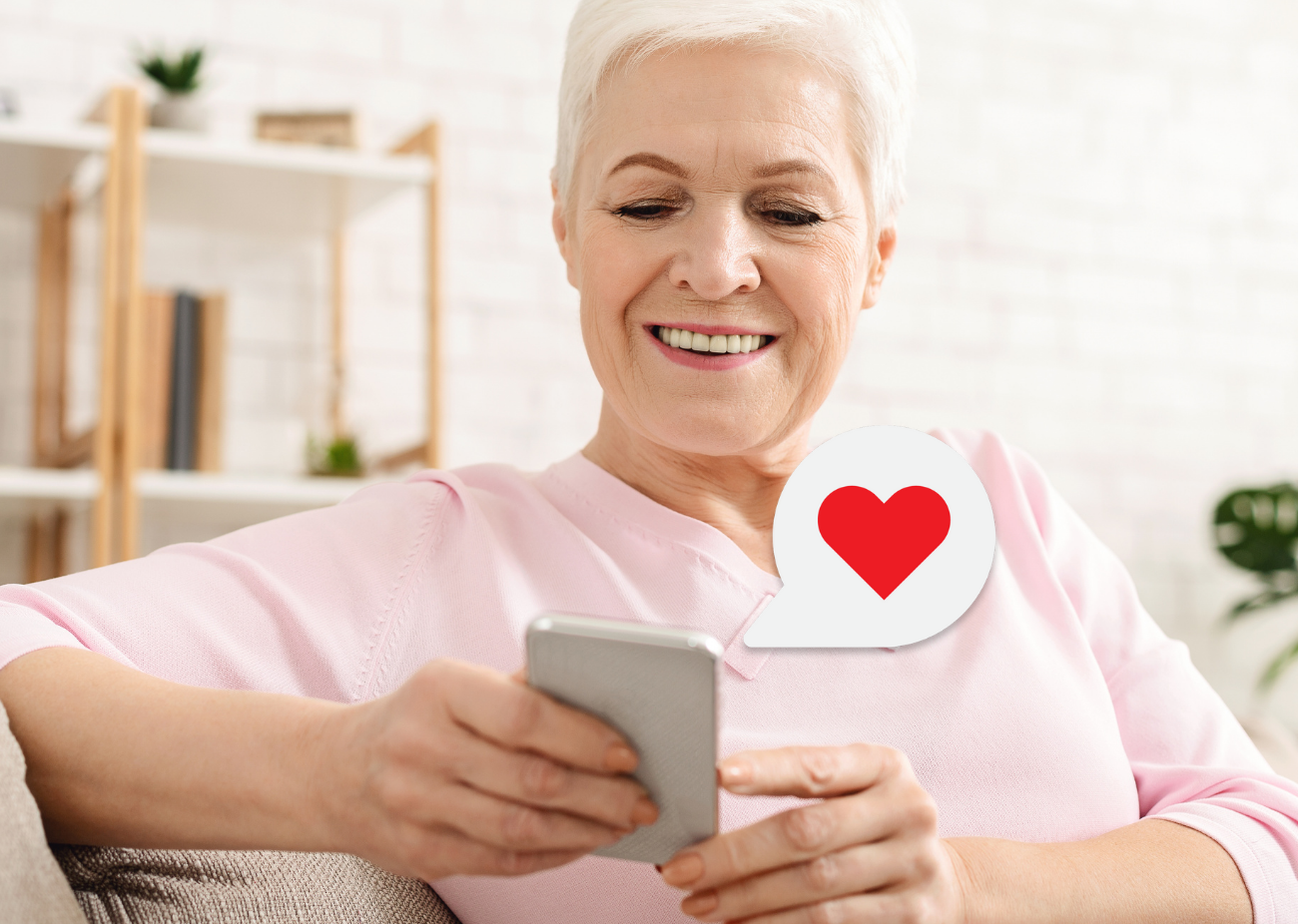 smiling older woman looking at her cellphone with a heart emoji