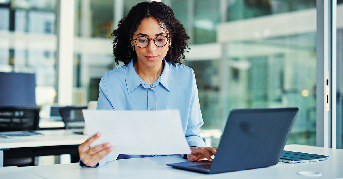 woman reviewing documents and working at a laptop