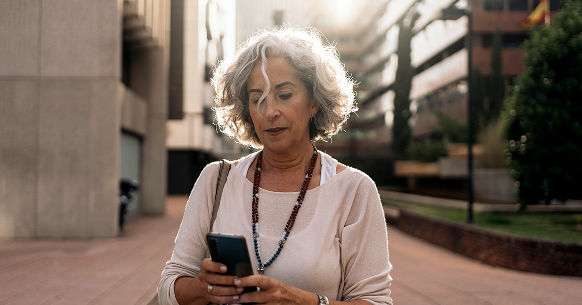 woman looking at her phone while walking near office buildings