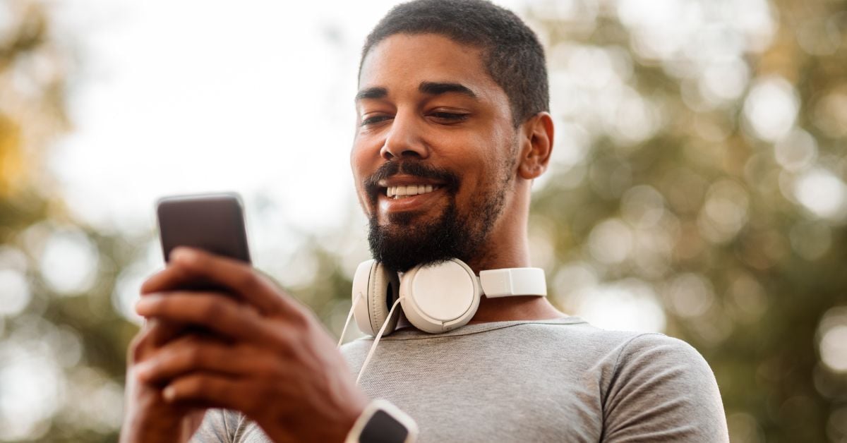 a smiling man using a cellphone while outside