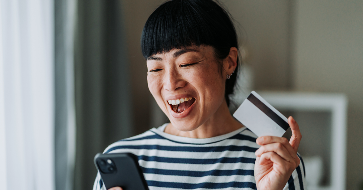 smiling young lady holding a credit card and phone