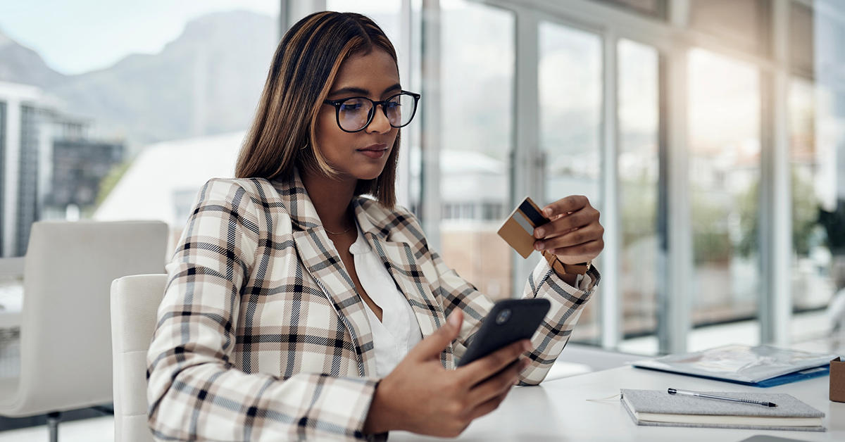a woman holding a credit card and viewing her phone