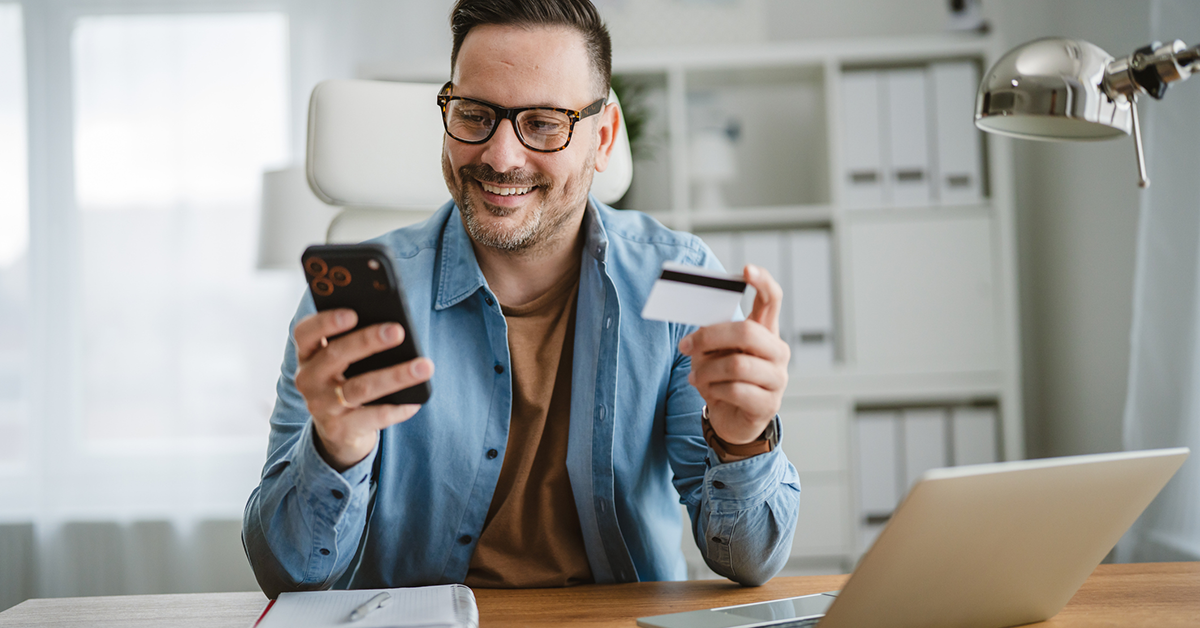 man working on his phone while holding a credit card