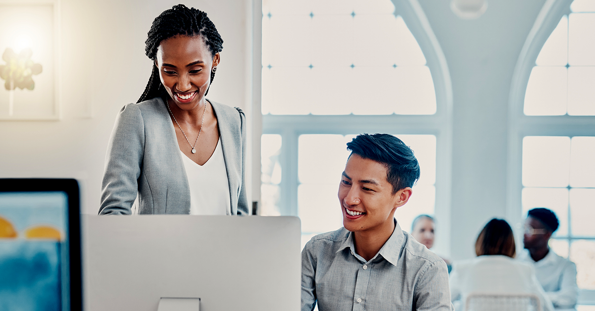 two people in an office collaborating at a computer