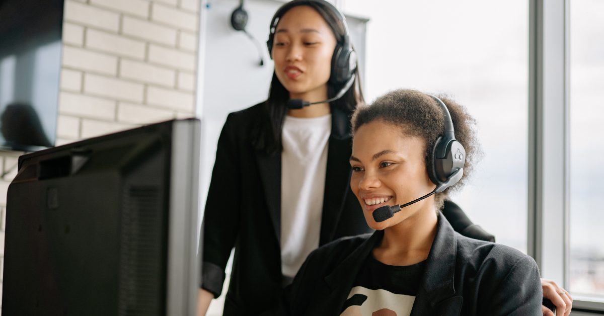 two contact center representatives reviewing a monitor