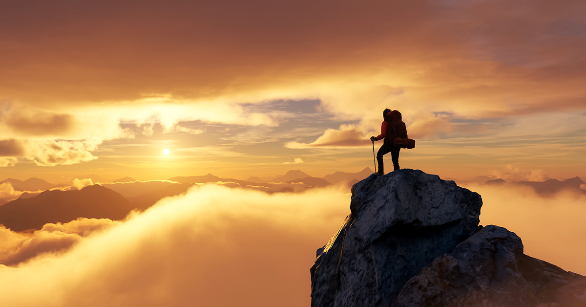 person ascending a mountain in the clouds