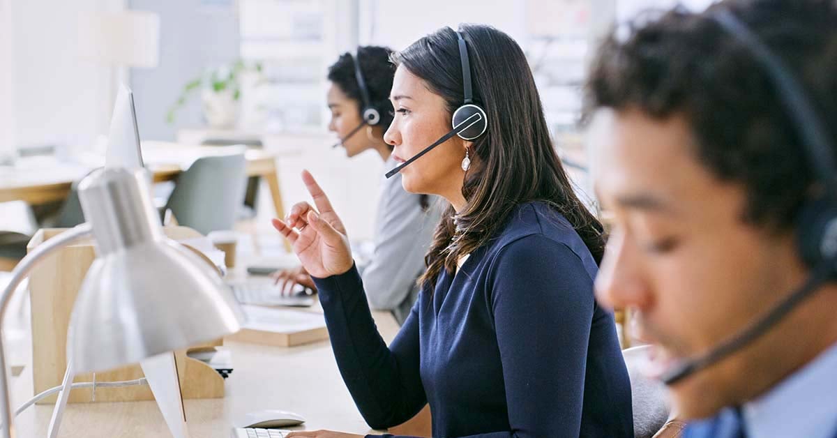 call center employees talking on headphones and looking at computer screens