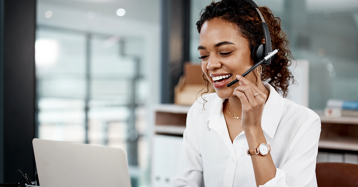 call center rep talking on headset while working on a laptop in an office