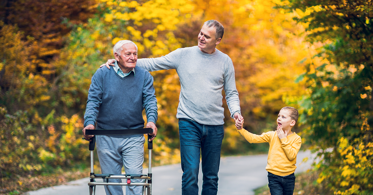 father, son and grandson walking a paved trail in the fall