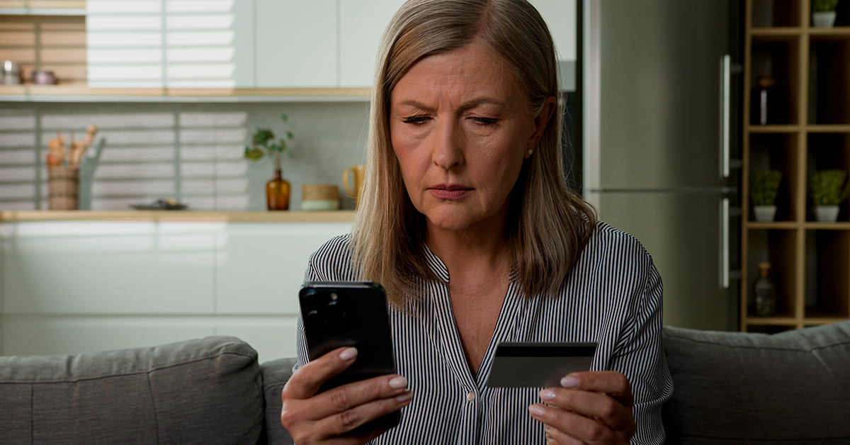 concerned woman looking at her phone and credit card