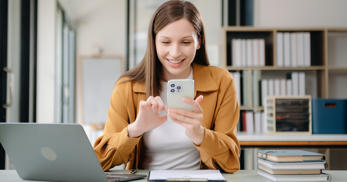 young woman smiling while working on her phone