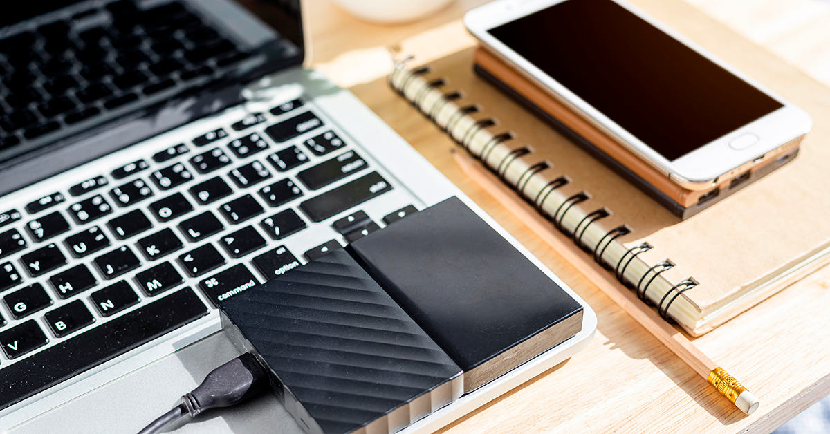 laptop, hard drive and phone on an office desk
