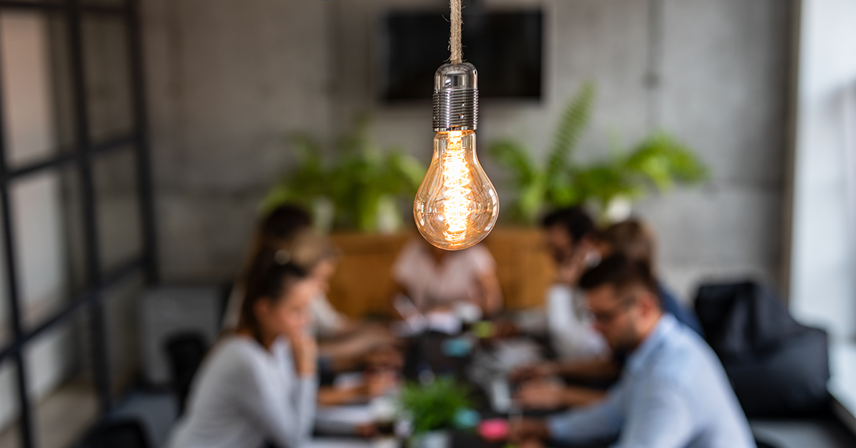 team meeting out of focus with a light bulb in the foreground