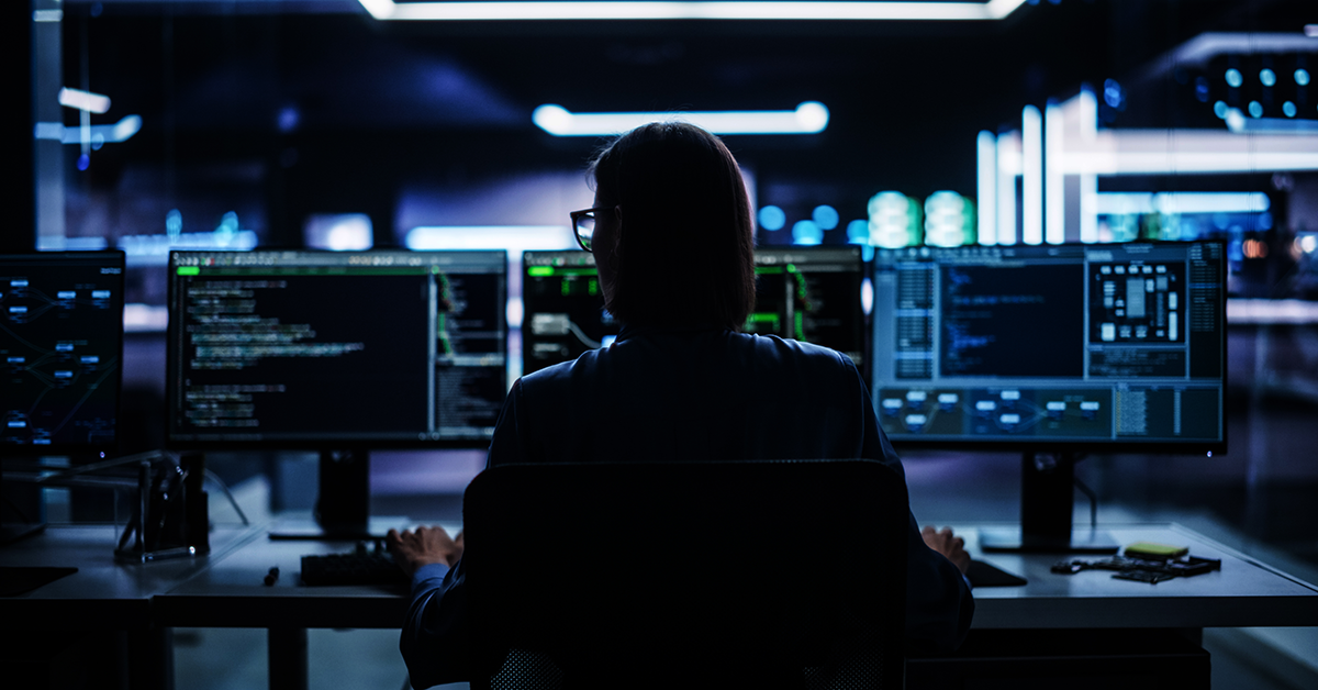 woman working at a computer desk in a darkened IT room