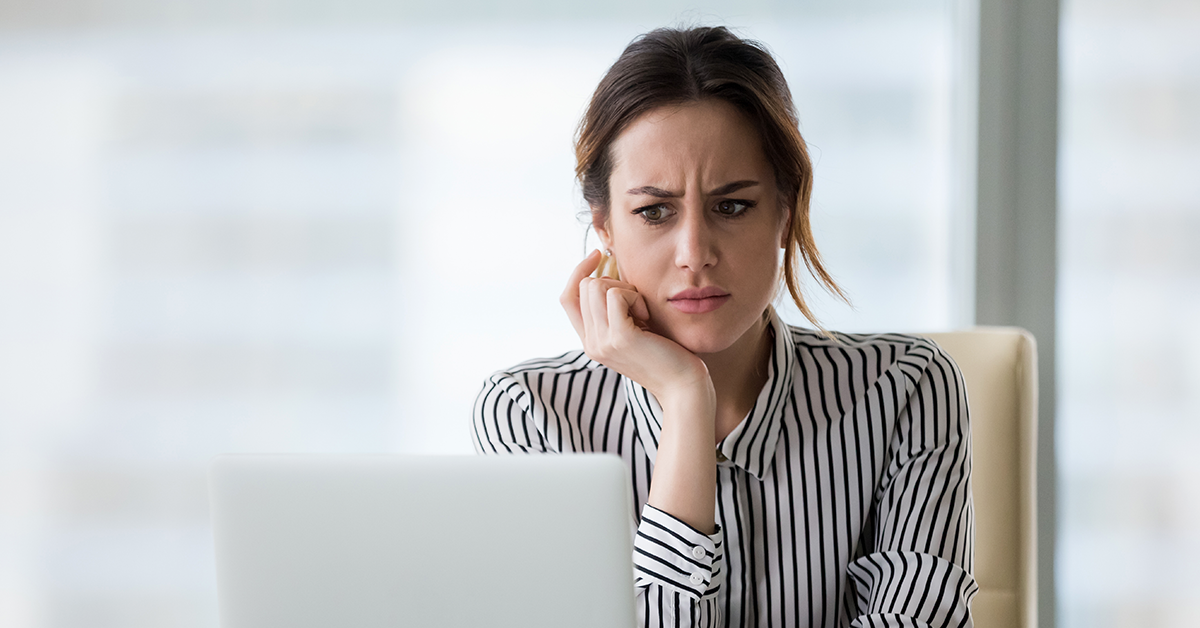 a woman looking at a laptop with a confused look