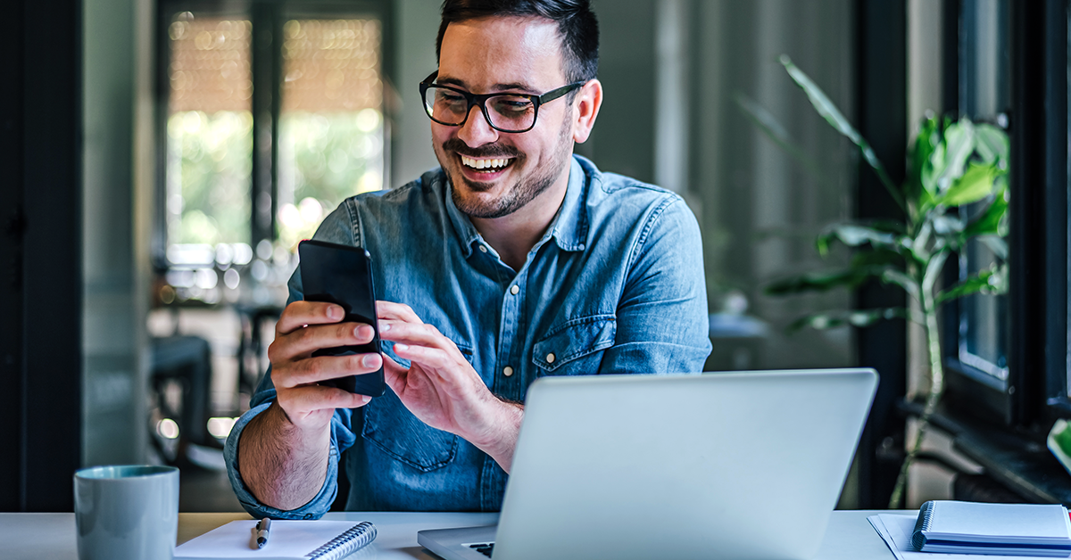 man smiling and looking at his phone in an office