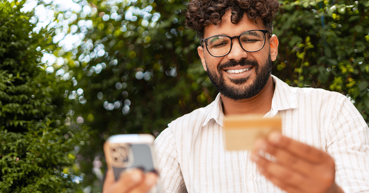 man using a phone and looking at his credit card