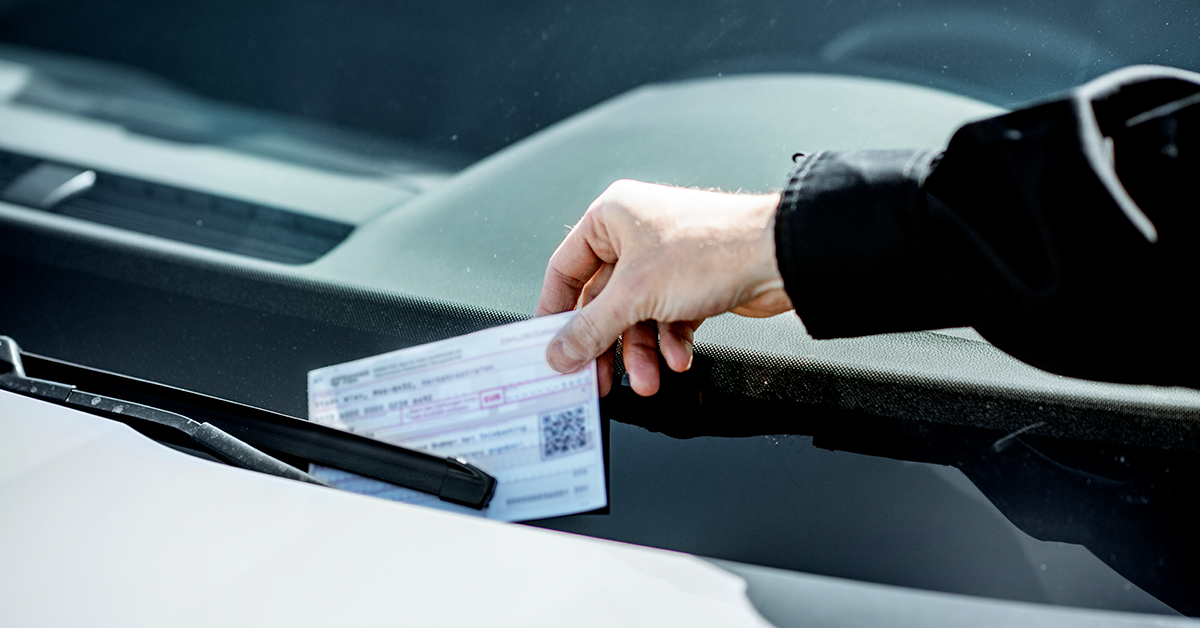 a parking ticket being placed on a car windshield