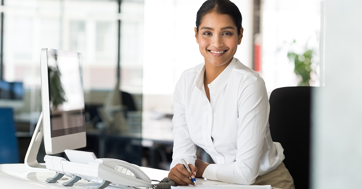woman sitting at a desk with phone and computer