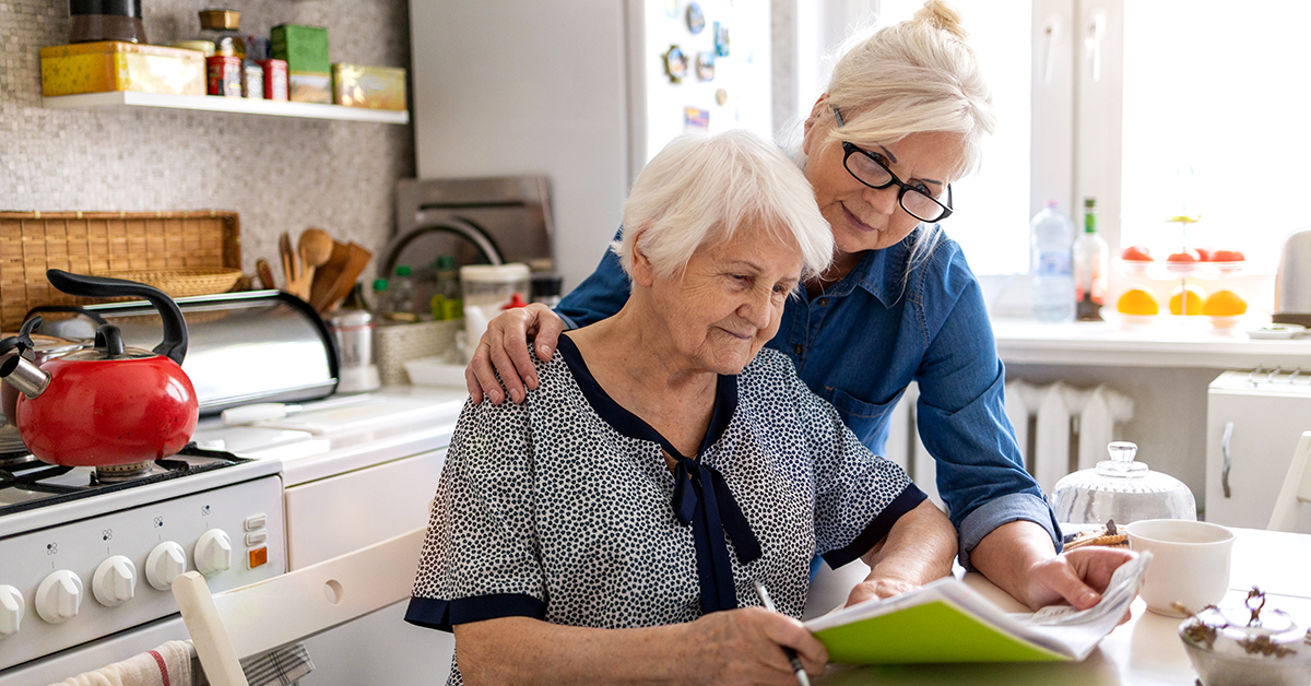 a woman helping her elderly mom review paperwork