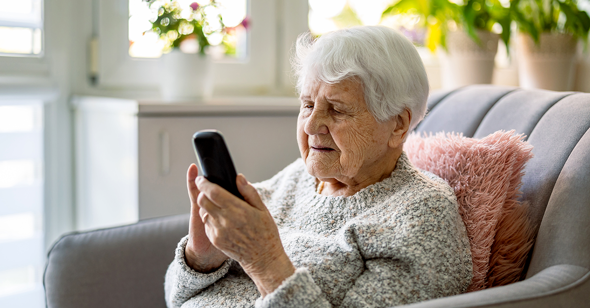 older woman sitting in a chair and looking at a phone
