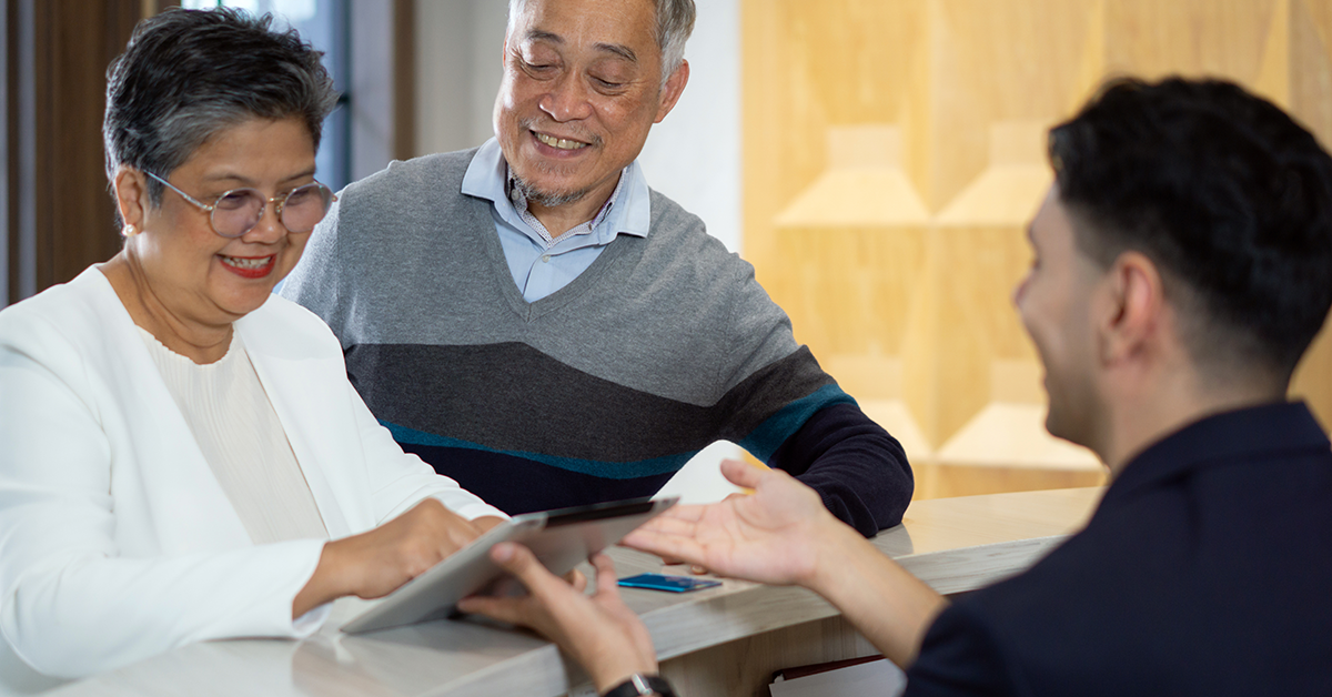 smiling senior couple at a counter conducting business