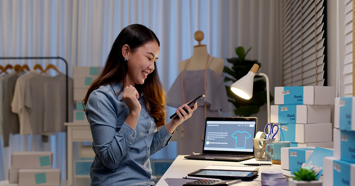 a small business owner looking at her phone in her place of business