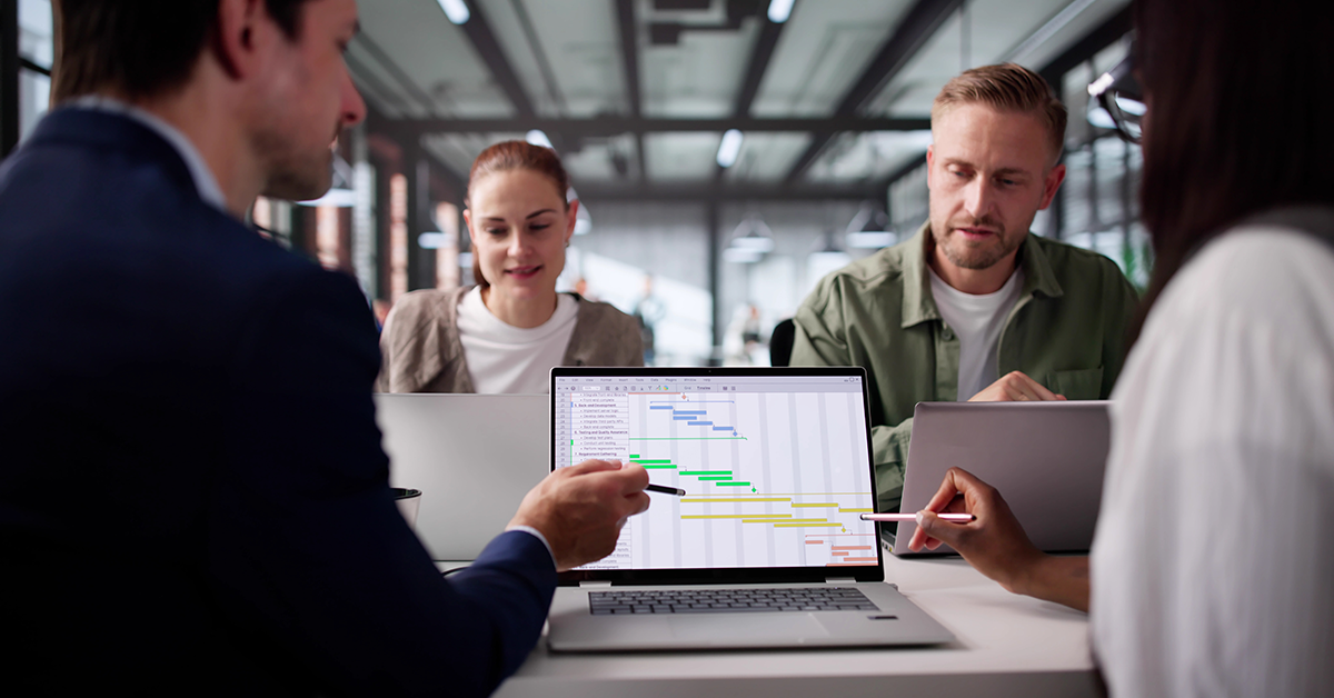 team meeting with a gannt chart showing on a laptop
