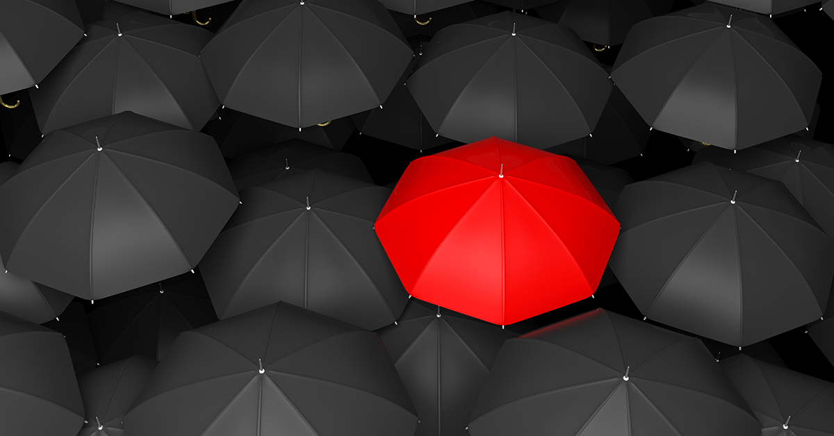 a red umbrella in the midst of black umbrellas