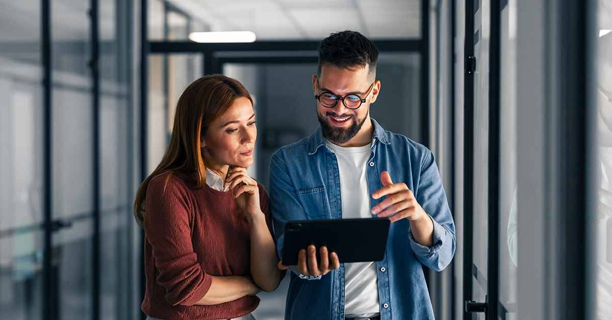 two professionals reviewing a tablet in a hallway